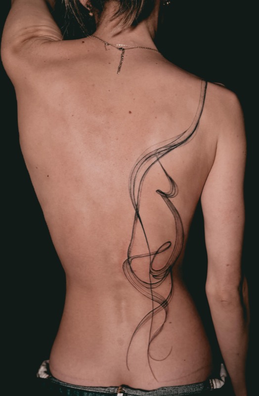 Flowing freehand fine line spine tattoo